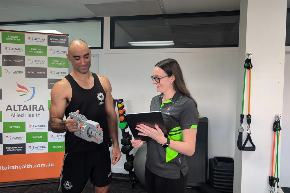 Clinician explaining VALD DynaMo handheld dynamometer strength testing